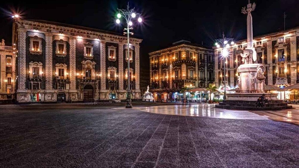 A grand plaza with ornate buildings, a central fountain, and street lamps. 1