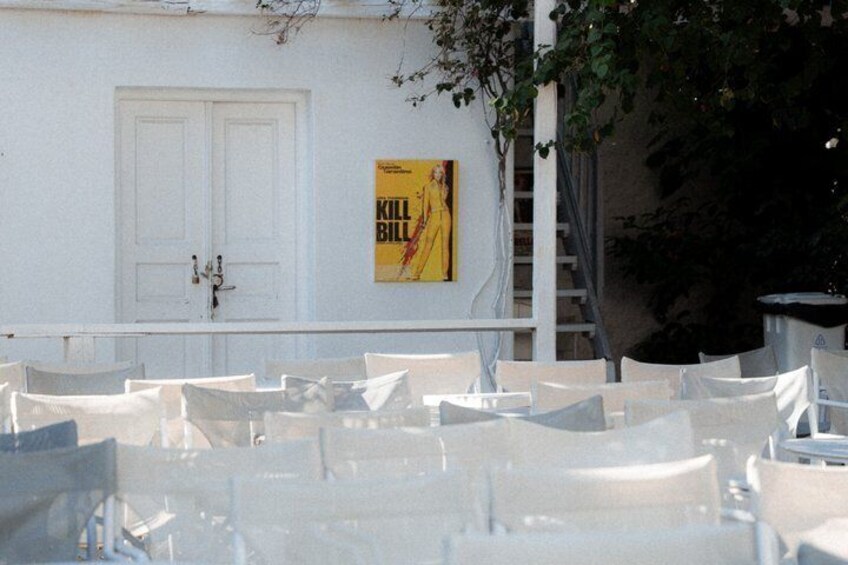 Outdoor tables and chairs, a white door, and a poster on the wall. 2