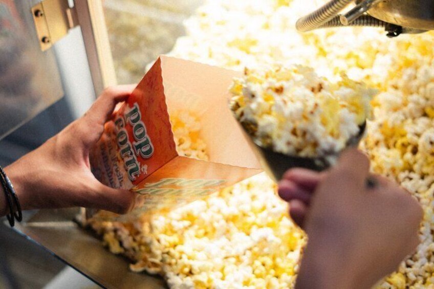 A person scooping popcorn from a container. 3