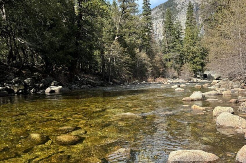 A clear river with rocks, surrounded by dense forest and mountains. 4