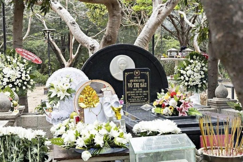 A cemetery with gravestones, flowers, and a memorial plaque. 4