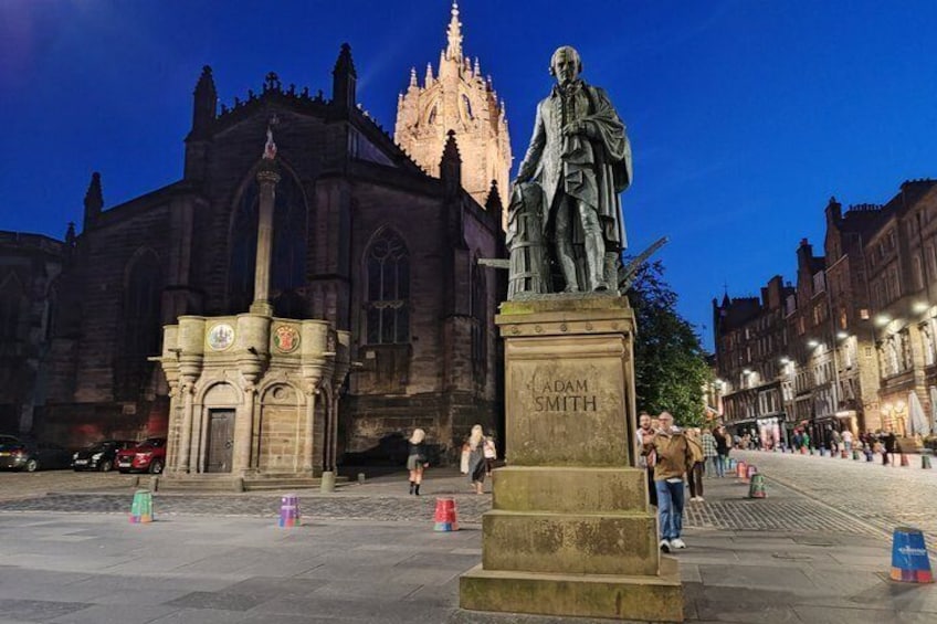 A statue of Adam Smith in a square with a historic building in the background. 5