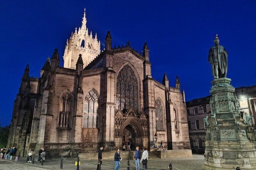 A historic cathedral with intricate architecture, a prominent statue, and a clear blue sky. 1