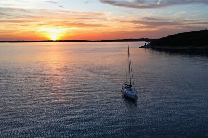 A sailboat on calm water during sunset. 1
