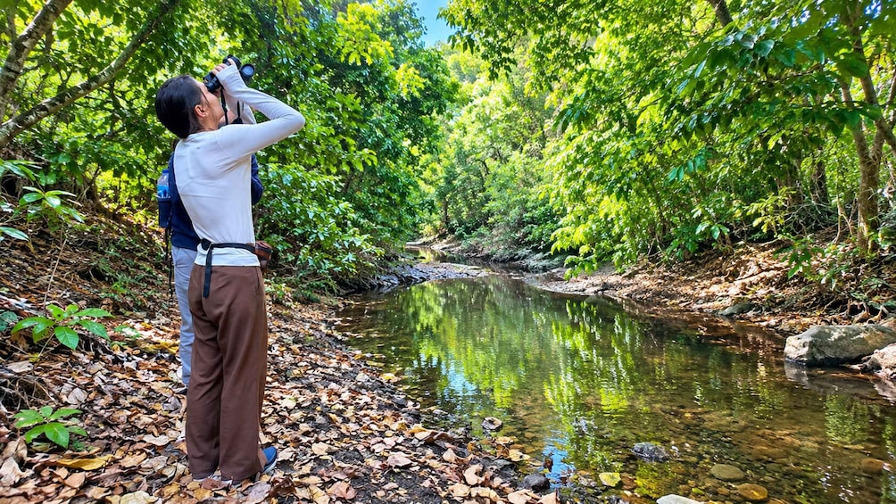 A person taking a photograph of a river surrounded by dense foliage. 2