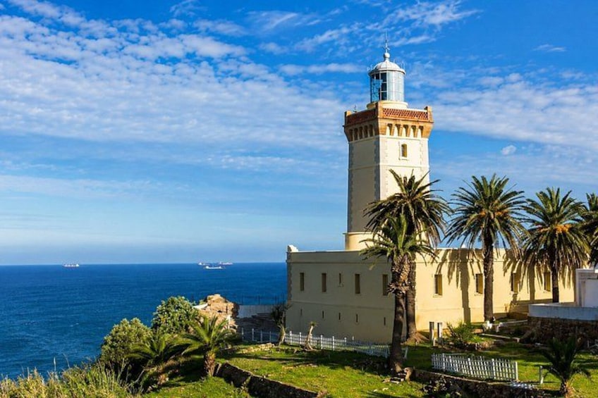 A lighthouse with a tower, palm trees, and the ocean in the background. 4