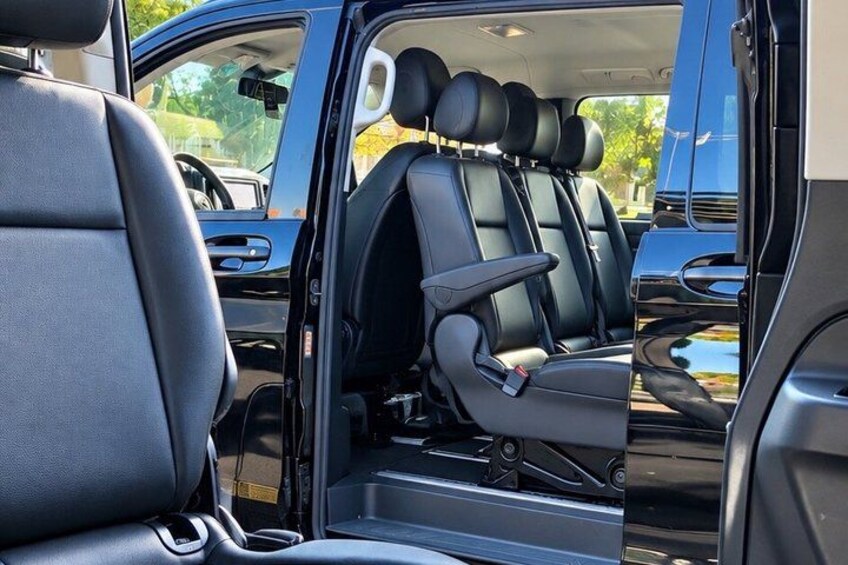 A vehicle interior with black leather seats, a sunroof, and a visible door handle. 4