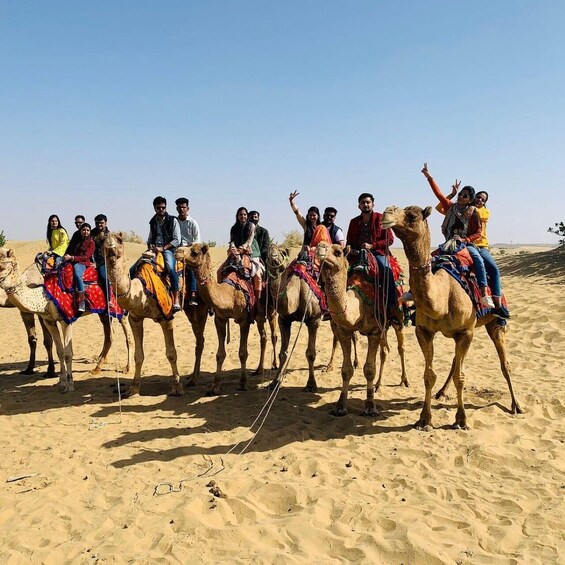 A group of people riding camels in a desert. 3