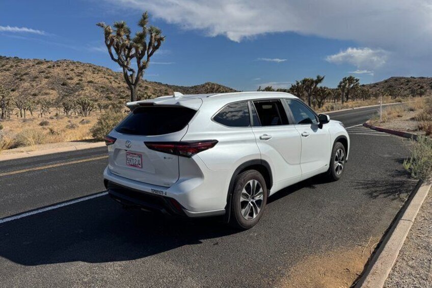 A white SUV parked on a road with a desert landscape in the background. 4