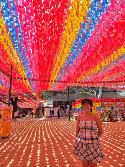 A person standing in front of a colorful installation with hanging lanterns. 3