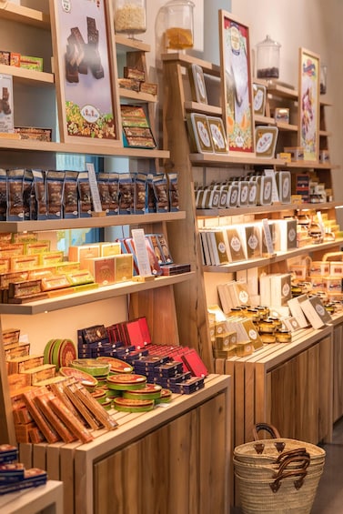 A variety of packaged goods on wooden shelves, including chocolates, nuts, and other snacks. 5