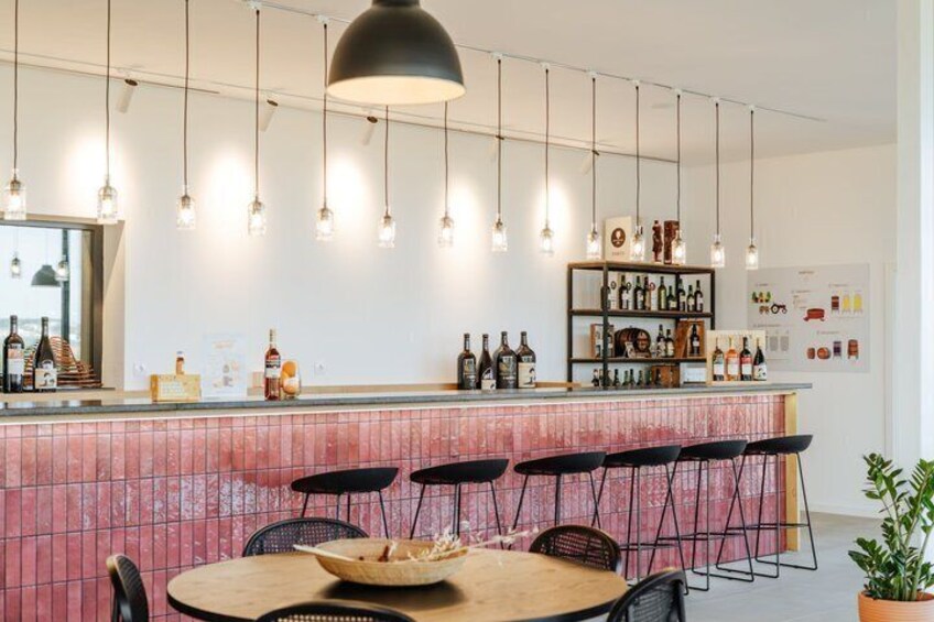 A bar with a red-tiled counter, hanging pendant lights, and black chairs. 3