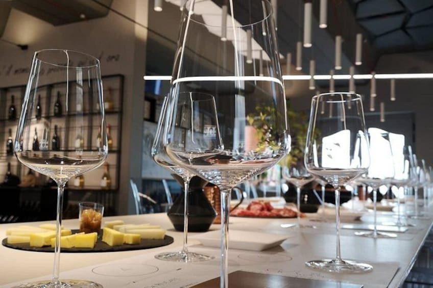 A bar setting with wine glasses, cheese, and bread. 2