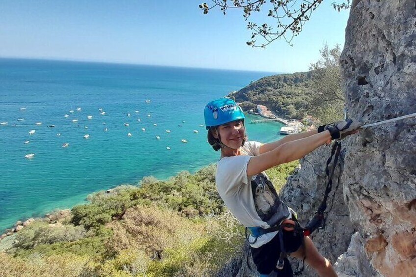 Una persona escalando en un risco con vista al mar y barcos. 1