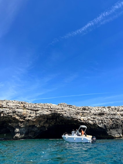 A boat anchored near a rocky coastline with clear blue skies. 4