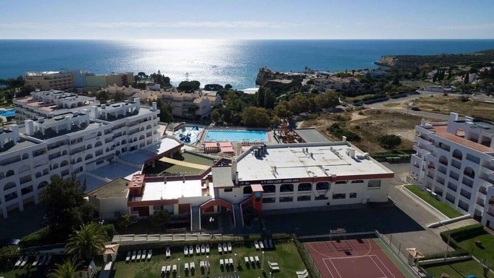 A coastal resort with a swimming pool, tennis courts, and a view of the sea. 2