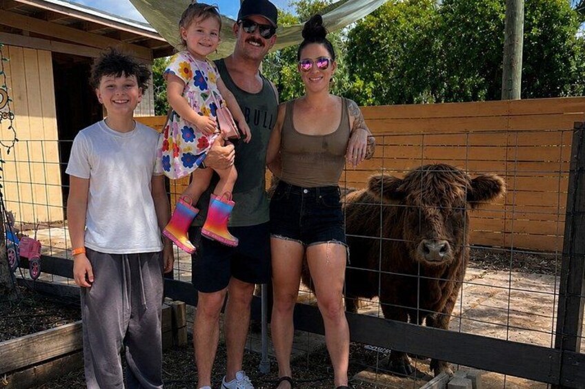 A family with a cow in a fenced enclosure. 3