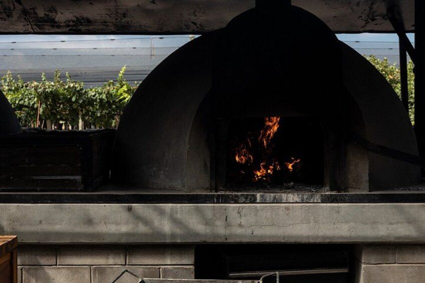 A stone oven with a fire burning inside, surrounded by a concrete structure. 5