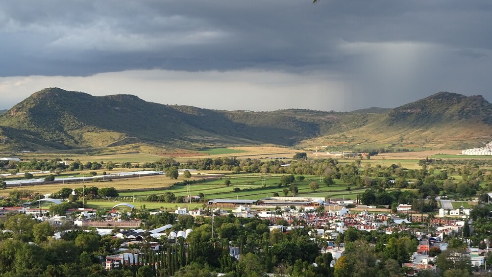 Un pueblo ubicado en un valle, con montañas al fondo y un cielo tormentoso. 4