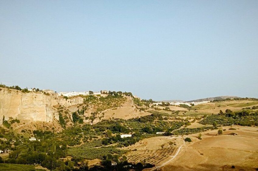 A mountainous landscape with terraced fields, a cliffside settlement, and a clear sky. 2