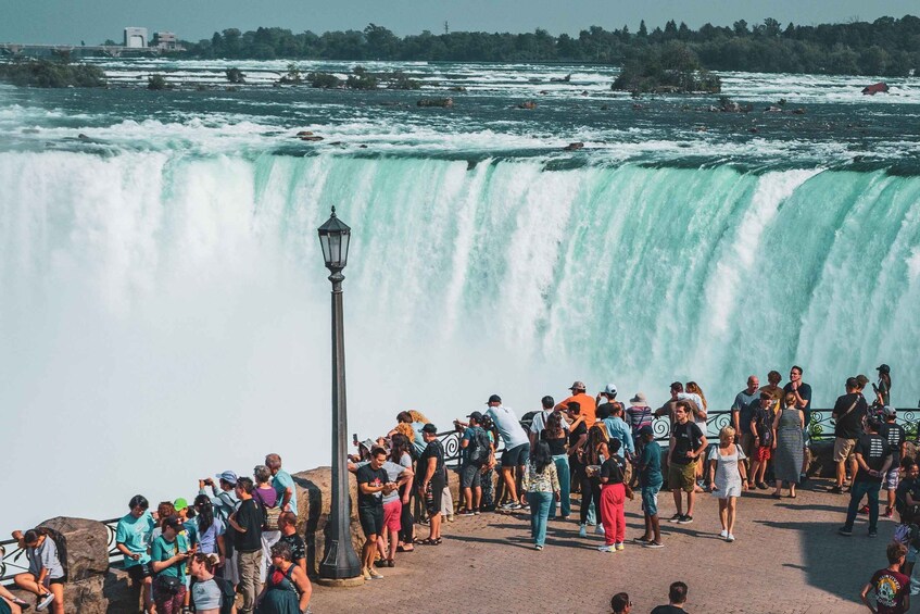 A large waterfall with people gathered around it. 2