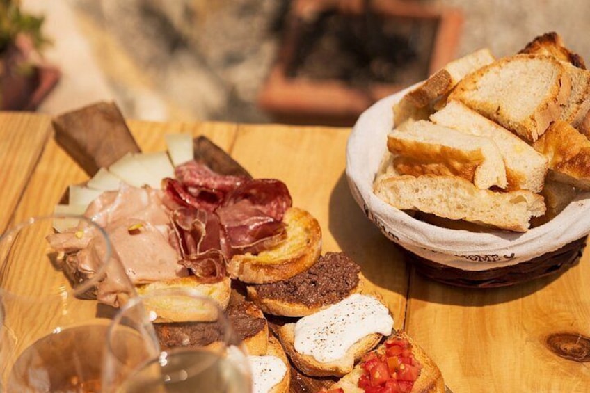 A wooden table with various food items including bread, cheese, and meats. 5