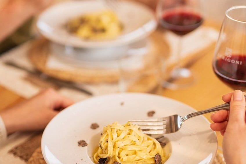A person holding a fork over a plate of pasta. 5