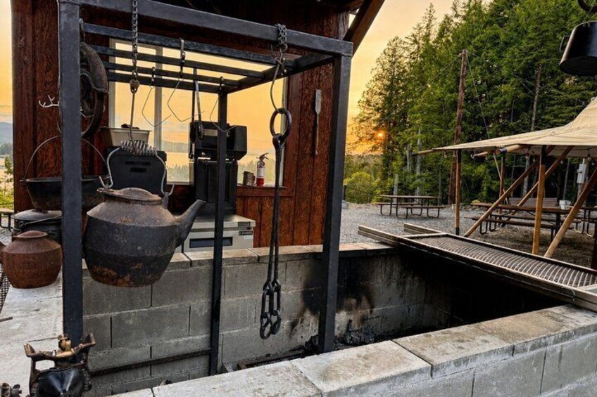 A rustic outdoor kitchen with hanging pots and a wooden structure. 4