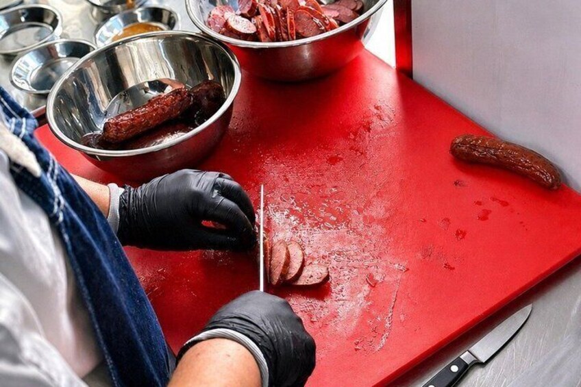 A person slicing sausage on a red cutting board with a knife. 2