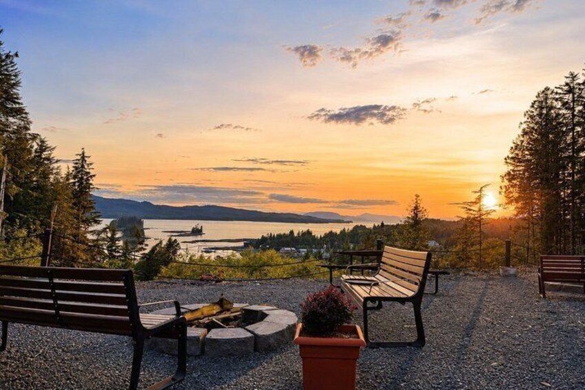 A sunset view with benches and a fire pit overlooking a lake. 1
