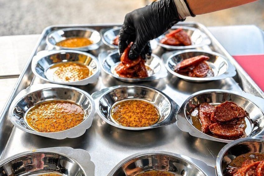 A tray with multiple small bowls containing different sauces and slices of meat. 5