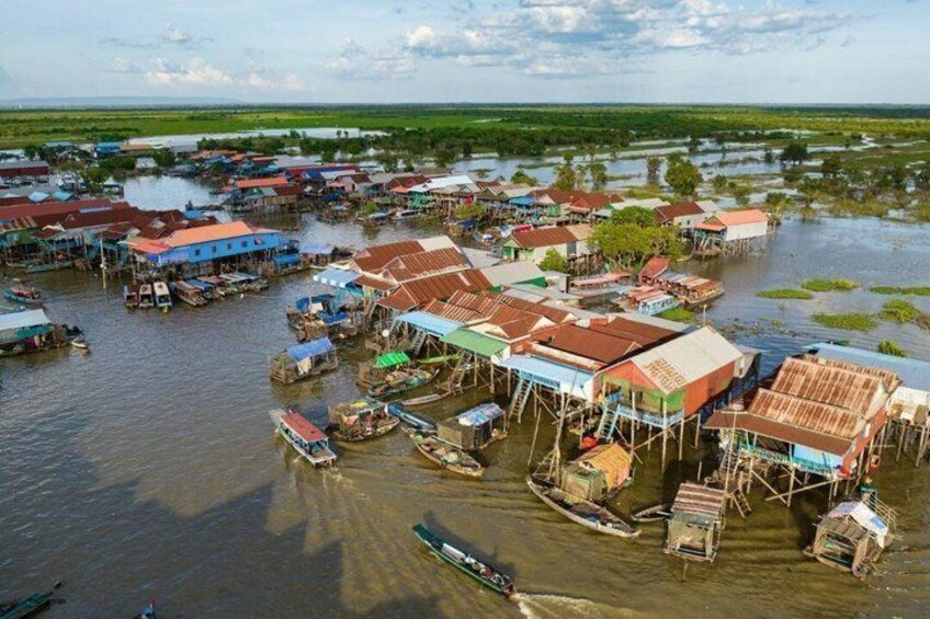 A floating village with houses on stilts over water, surrounded by greenery. 1