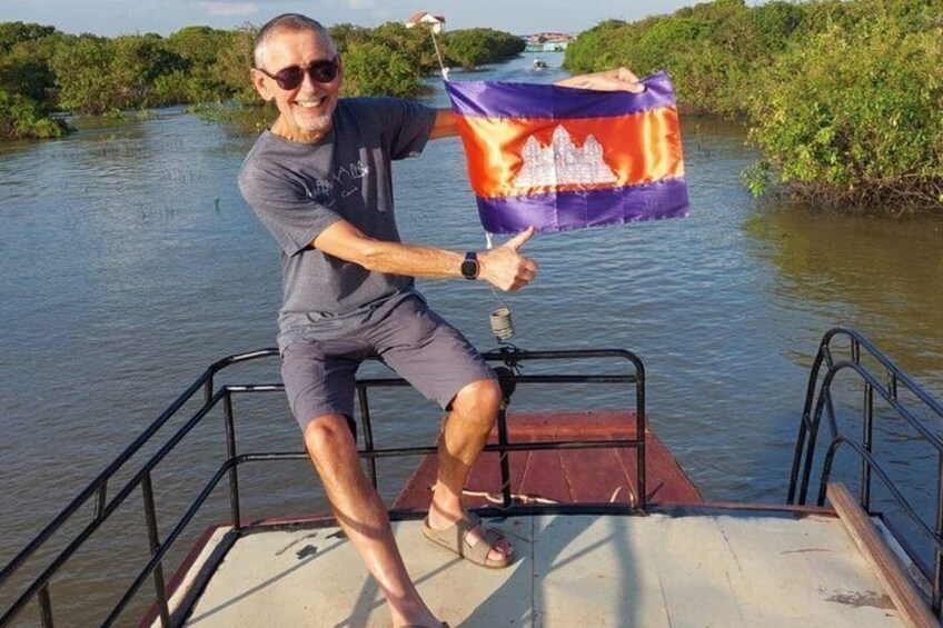 A person on a boat holding a flag, surrounded by water and greenery. 2