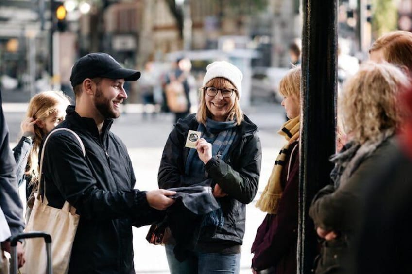 A group of people standing on a street, some holding a camera or phone. 2
