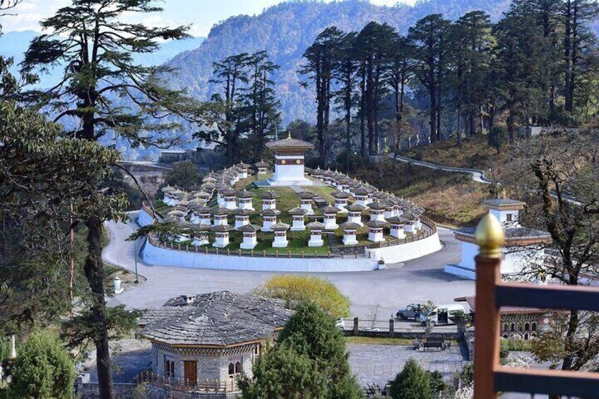 A mountainous landscape with a circular arrangement of buildings, a prominent central structure, and a road leading to the buildings. 3
