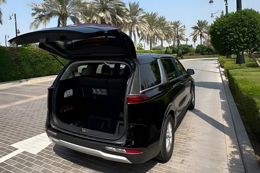 A black SUV parked on a paved road with its trunk open. 2