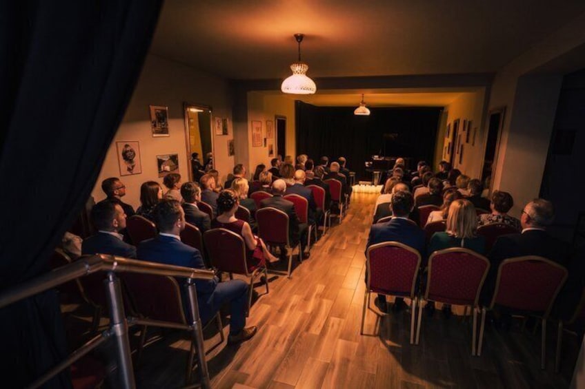 A room with people seated in rows facing a stage. 5