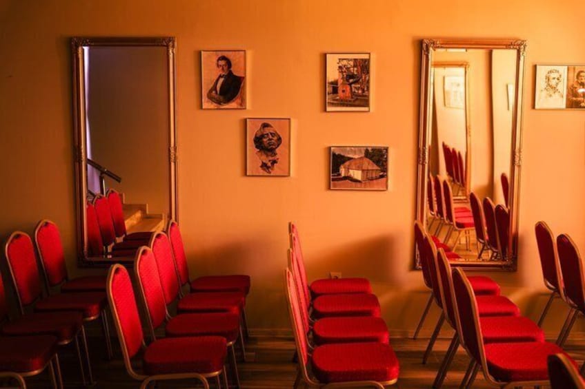 A room with red chairs, a mirror, and framed pictures on the wall. 2