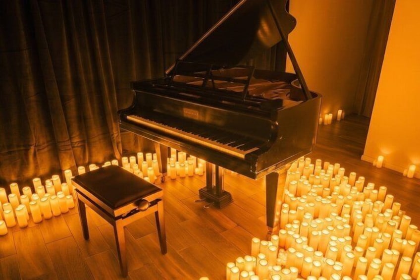 A grand piano surrounded by numerous lit candles on a wooden floor. 3