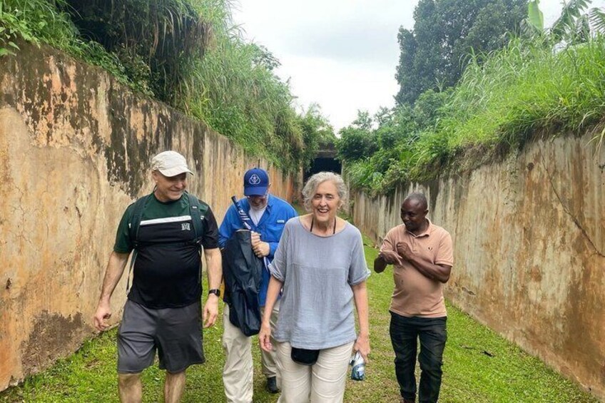 Four people walking along a narrow path bordered by a concrete wall and greenery. 4
