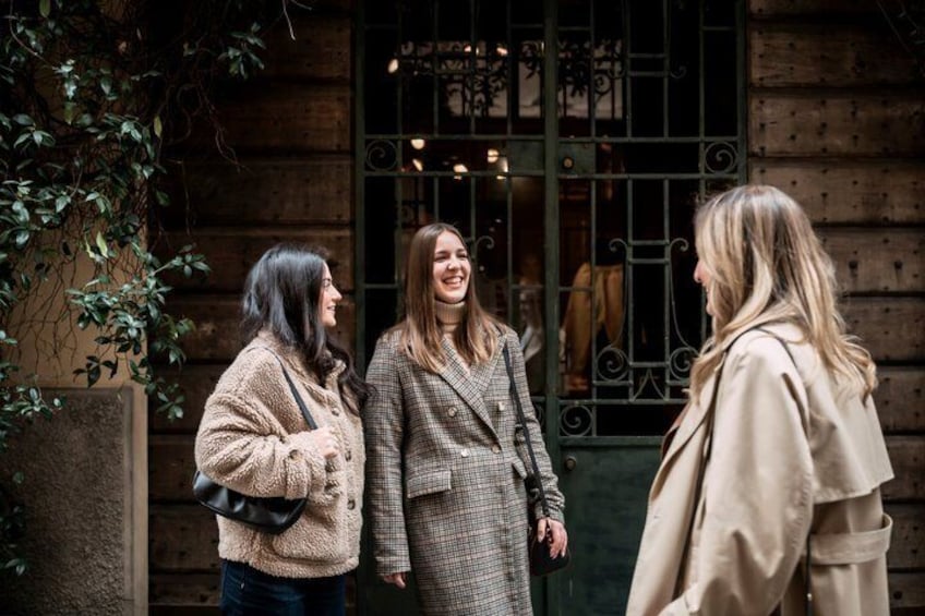 Three women standing in front of a wooden building with a wrought iron gate. 2