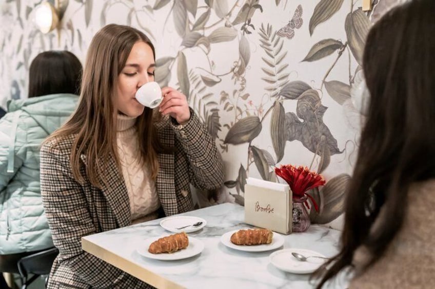 A person sitting at a table with a cup, a plate with a croissant, and a name card. 4