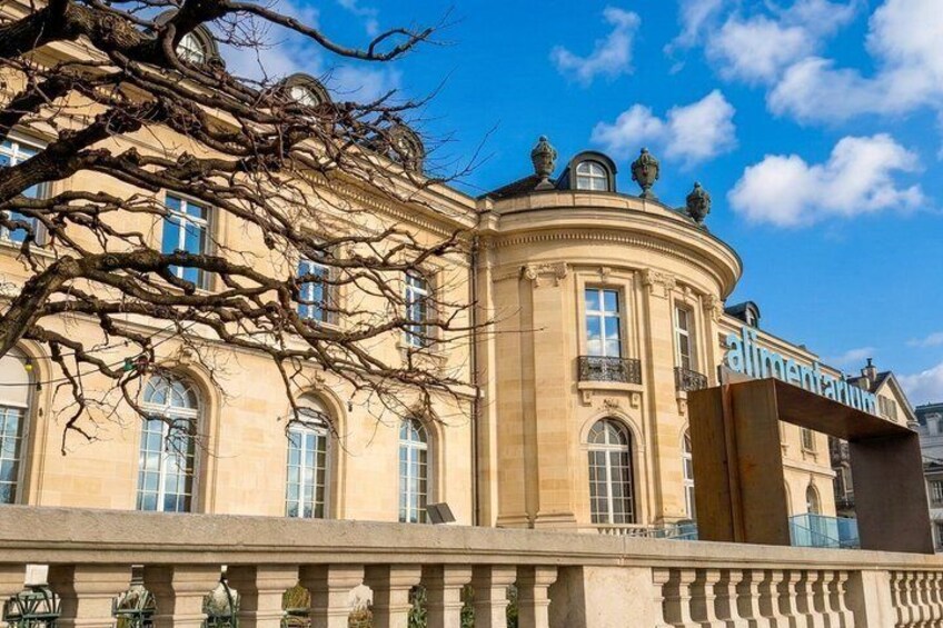 A classical building with arched windows and a balcony, surrounded by a clear blue sky. 5