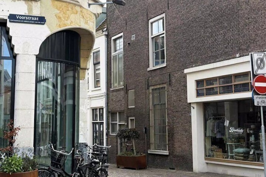 A street scene with a building labeled 'Voorstraat,' a no-entry sign, and bicycles parked outside. 4