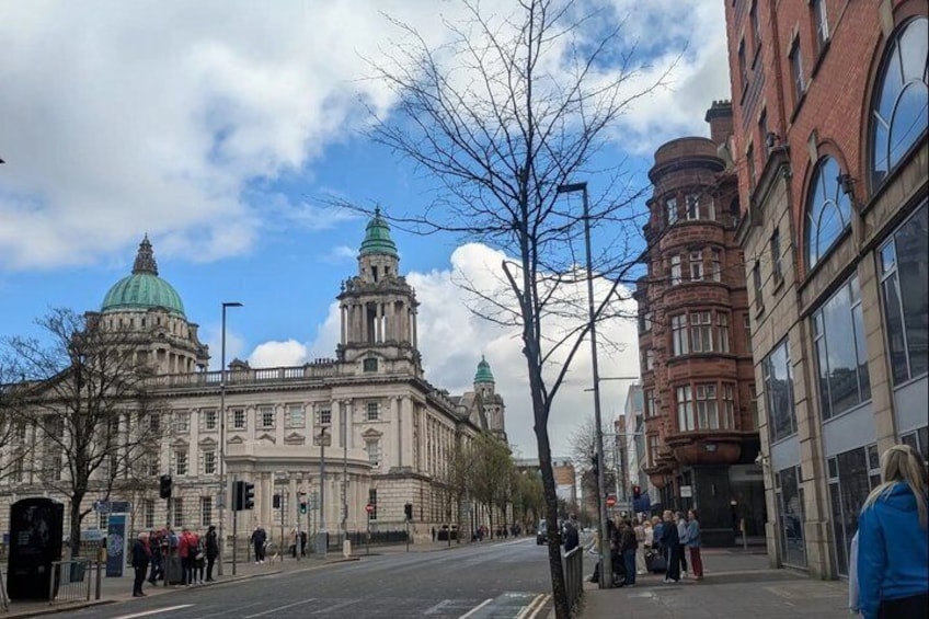 A historic building with domes, a street with pedestrians, and modern buildings. 5