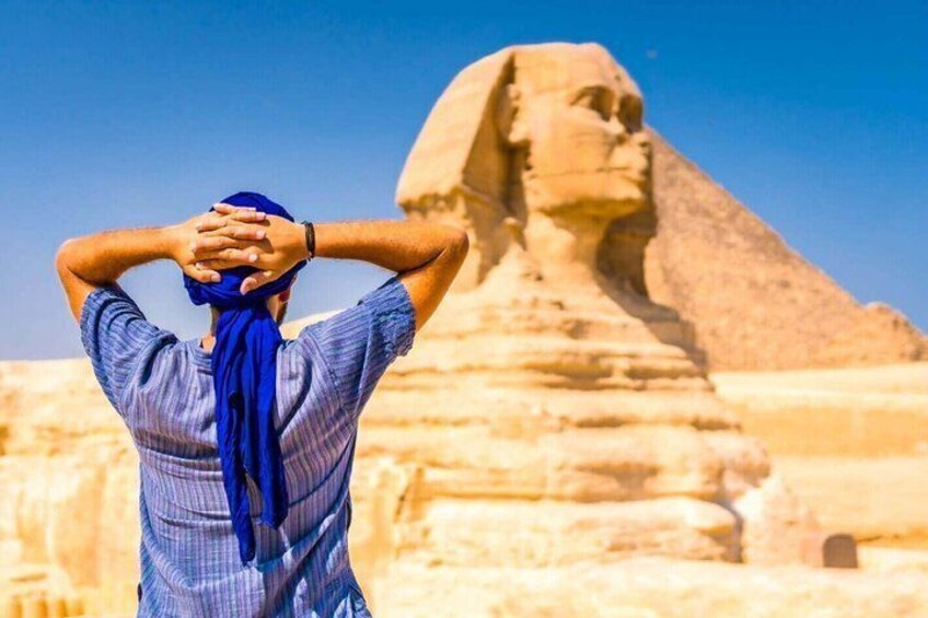 A person with a blue scarf standing in front of the Great Sphinx. 4