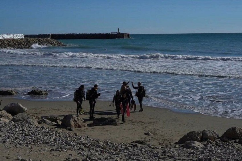 A beach with people walking along the shore, waves crashing onto the sand, and a pier in the background. 5