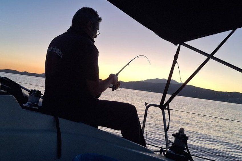 A person fishing on a boat during sunset. 3