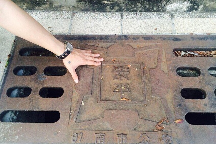 A hand touching a metal grate with Chinese characters and the number 97. 4