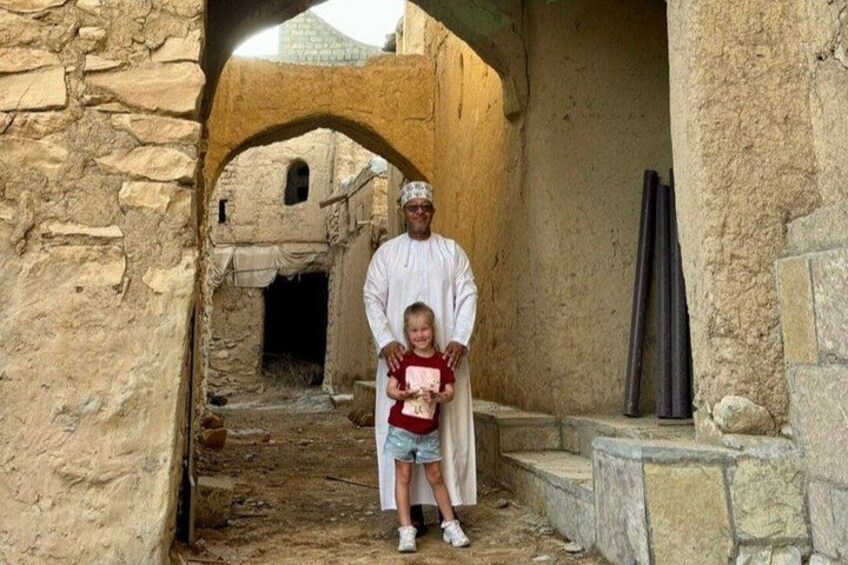Un antiguo arco de piedra, una persona vestida con atuendo tradicional y un niño con camisa roja. 5